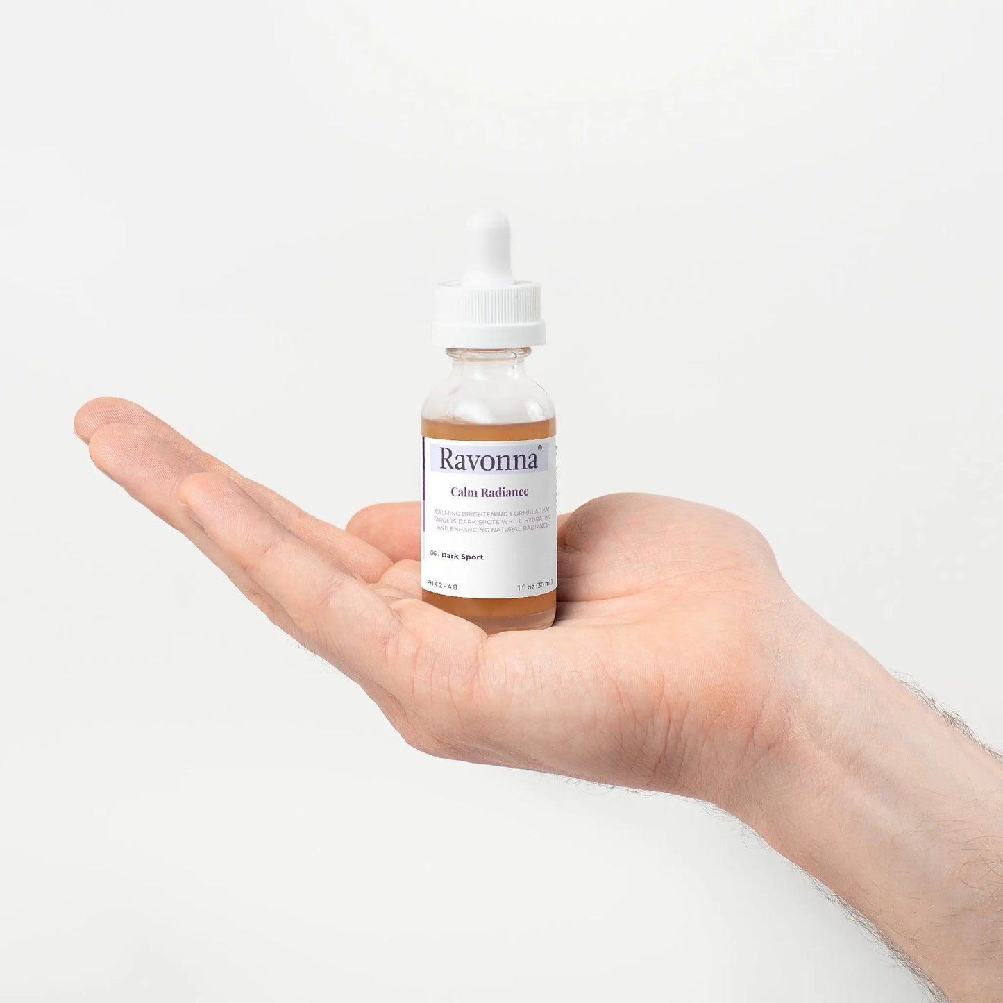 Calm Radiance Serum bottle in hand, white background – Ravonna