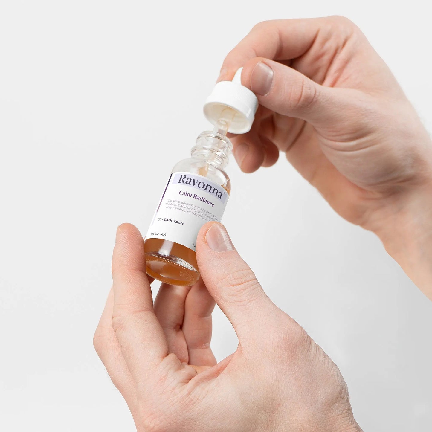 Hands holding Calm Radiance Serum bottle – Ravonna
