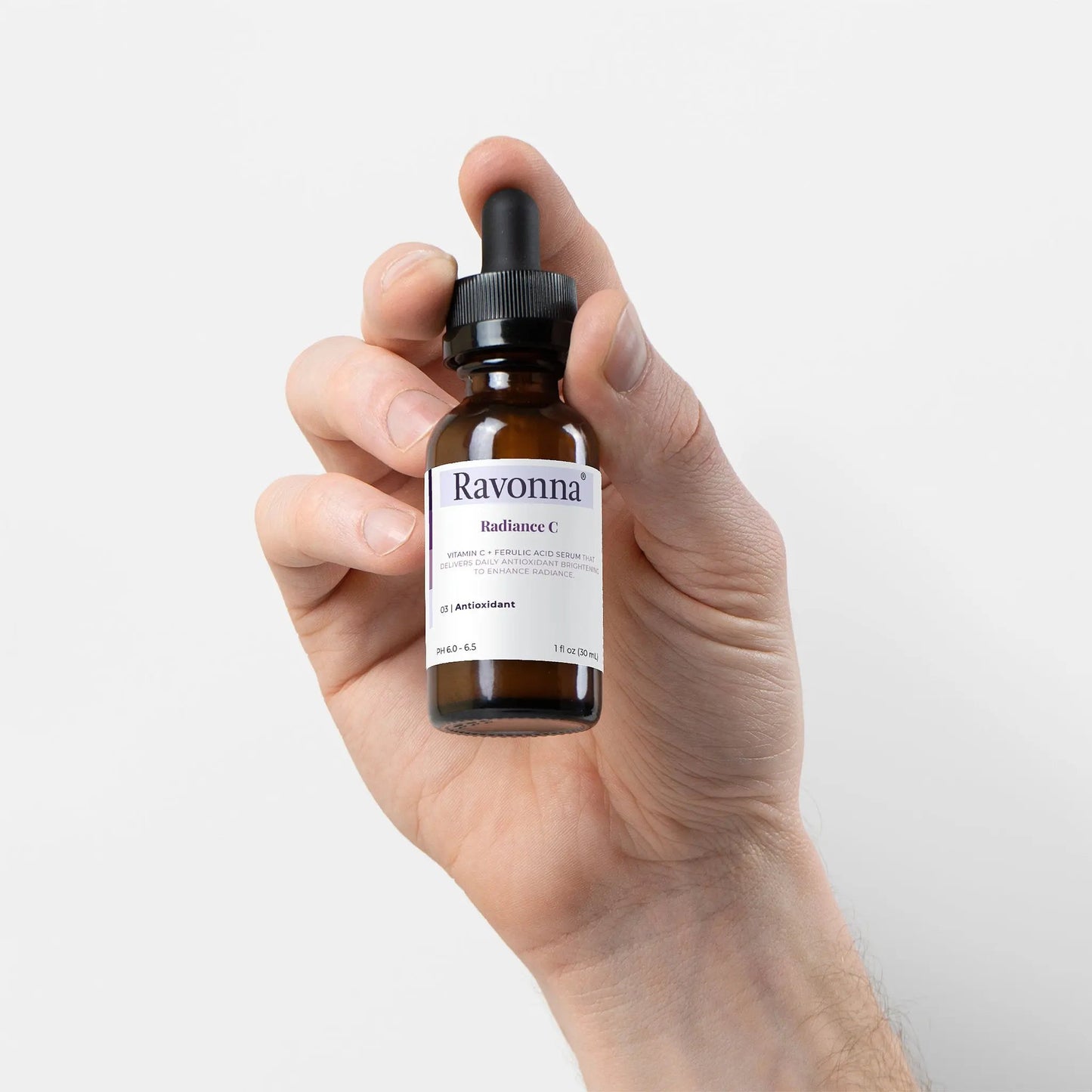 Hand holding Radiance Serum close-up – Ravonna