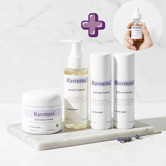 Ravonna skincare products on a marble tray with a hand holding a bottle.